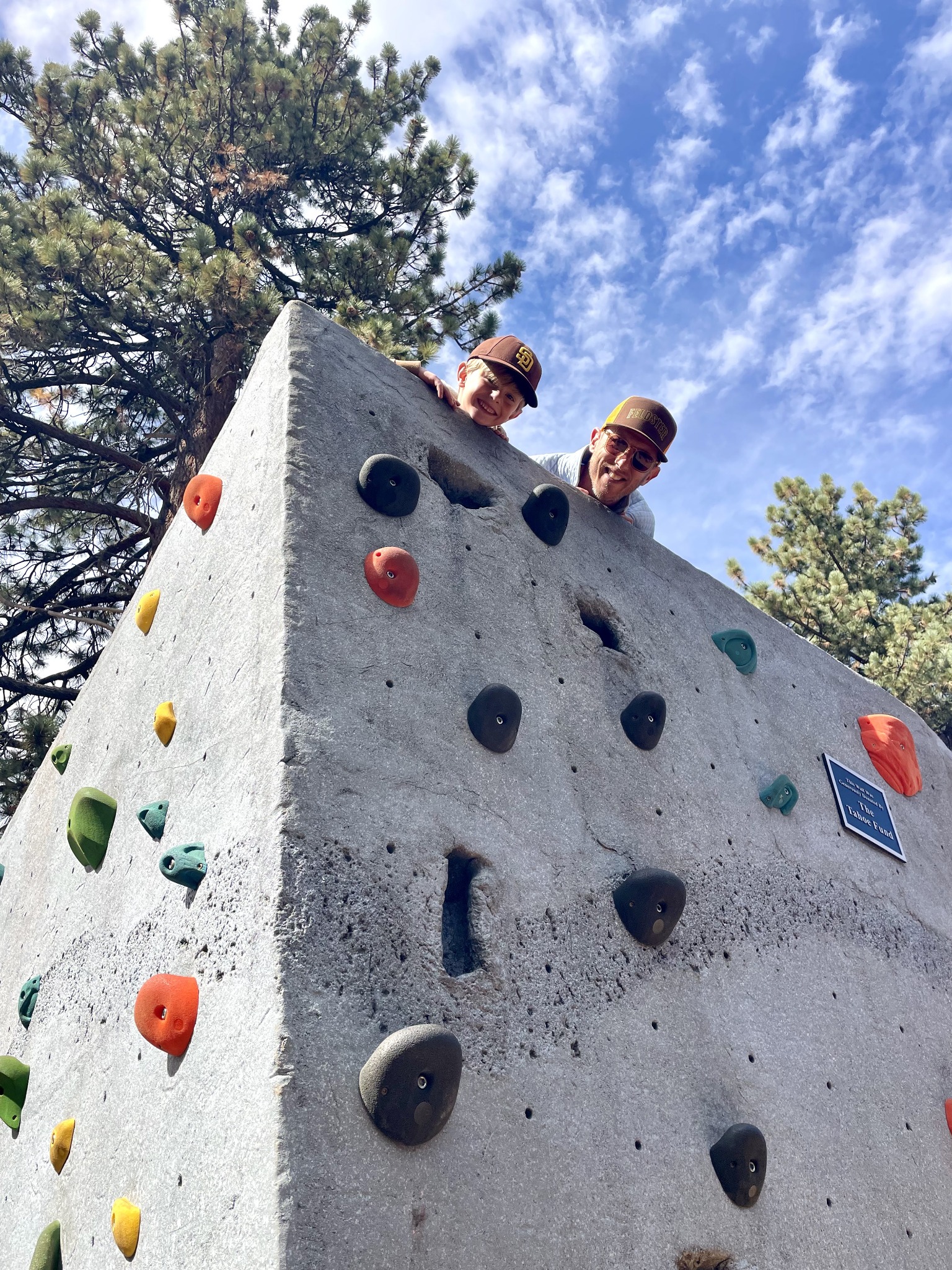 Skye and his dad peeking over a climbing wall in Lake Tahoe